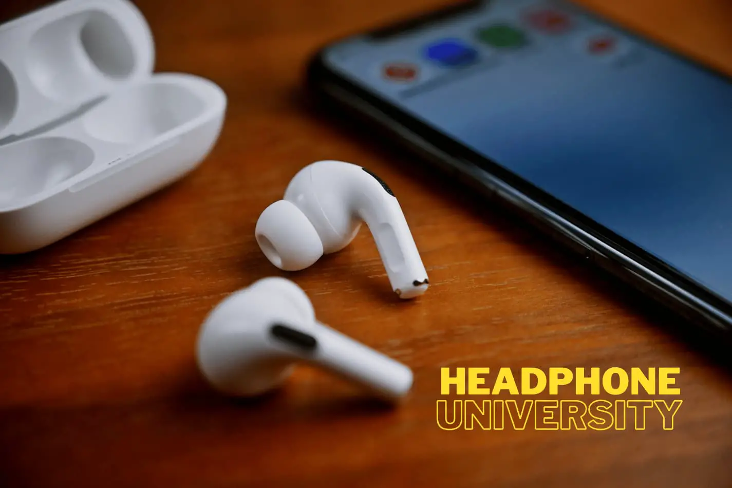 airpod pros volume control Airpod Pros on table next to charging case and cell phone.